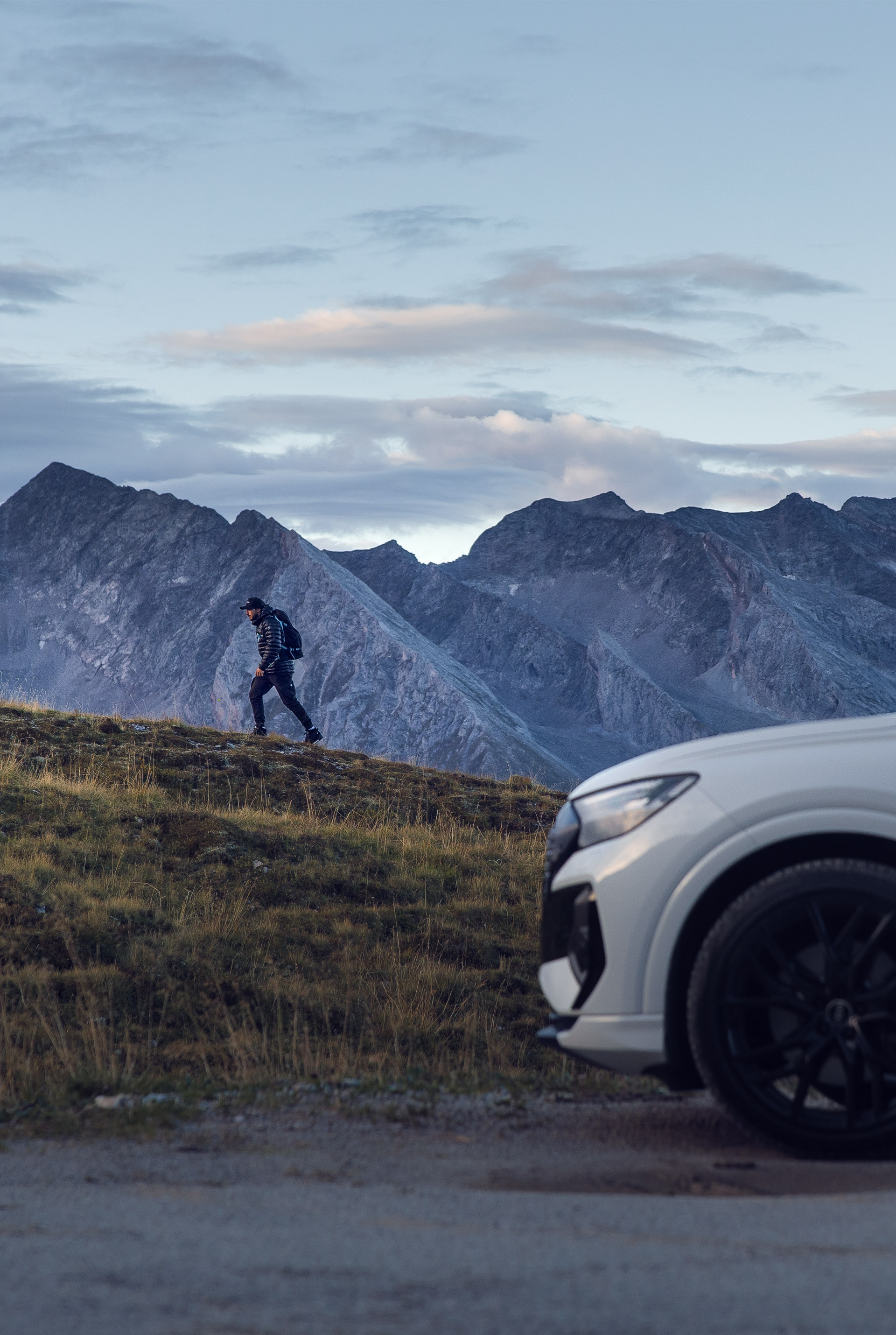 Tom Klocker wandelt een berg op vanaf zijn geparkeerde witte Audi Q4 e-tron.